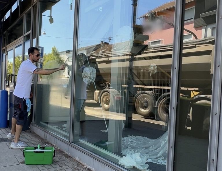 Antonio La Gaipa reinigt mit dem Einwascher die Schaufensterfront eines Ladenlokals an einer Durchgangsstraße in Neunkirchen.